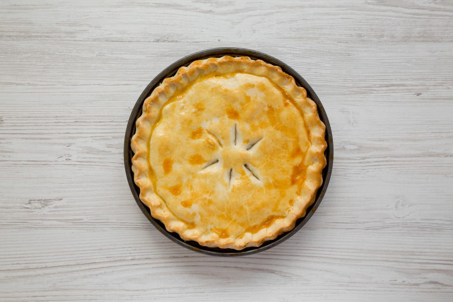 A Piece of Chicken Pot Pie on a white wooden background, top view. Flat lay, overhead, from above.