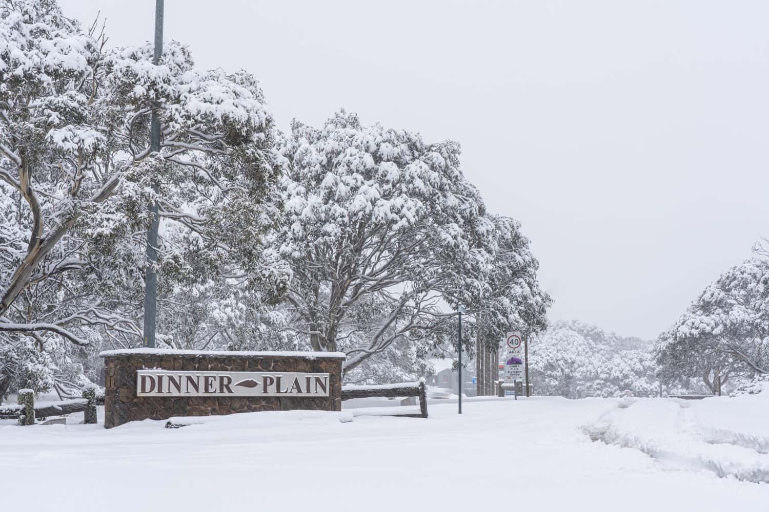 The entrance area to Dinner Plain in Victoria, Australia with a stone sign in snowy winter
