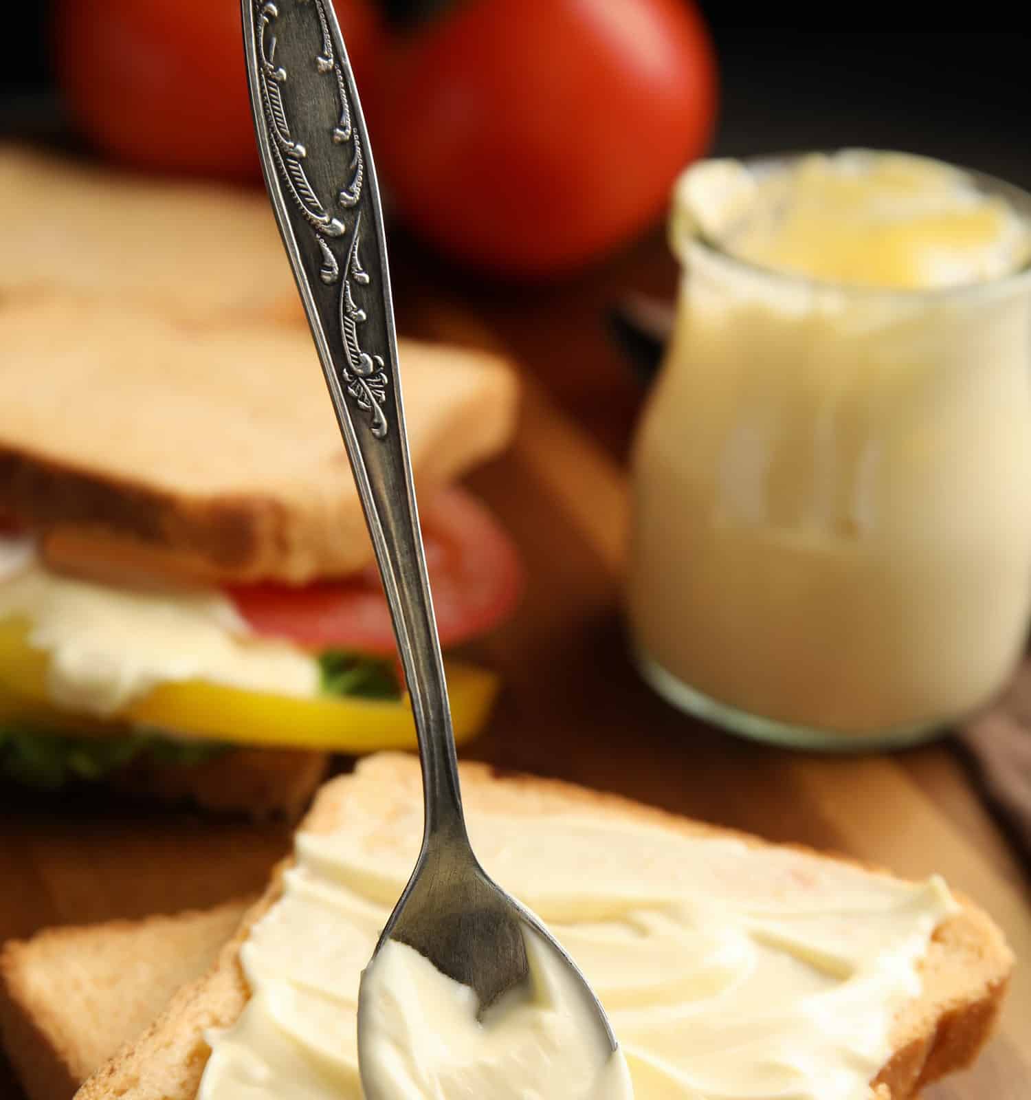 Slices of bread with mayonnaise on wooden table, closeup