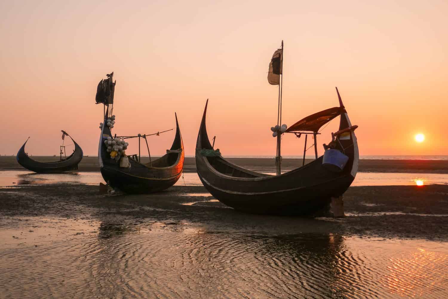 Sunset with beautiful traditional wooden fishing boats known as moon boats on beach near Cox's Bazar in southern Bangladesh	