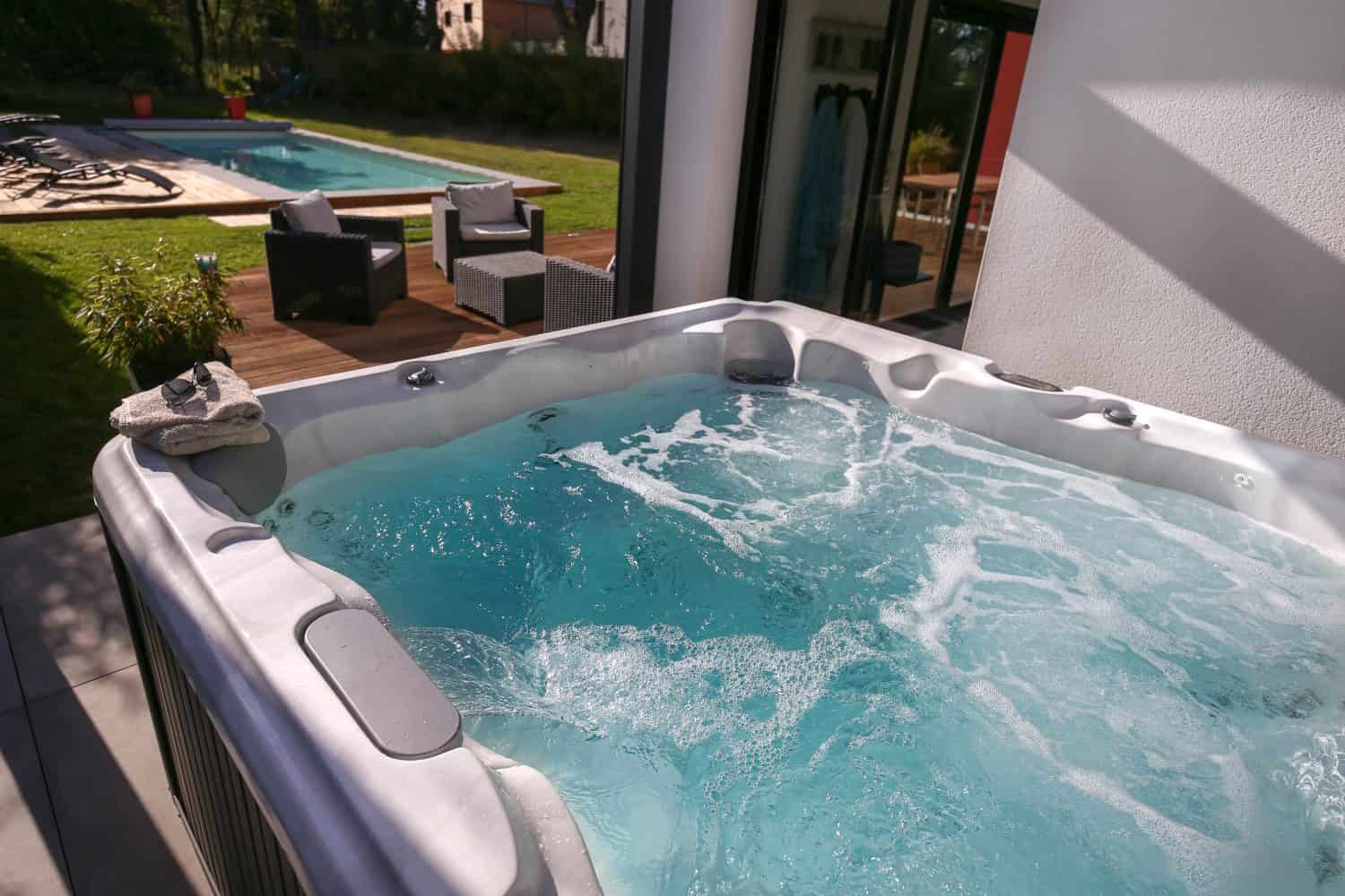 hot tub on outdoor terrace with swimming pool next to the house