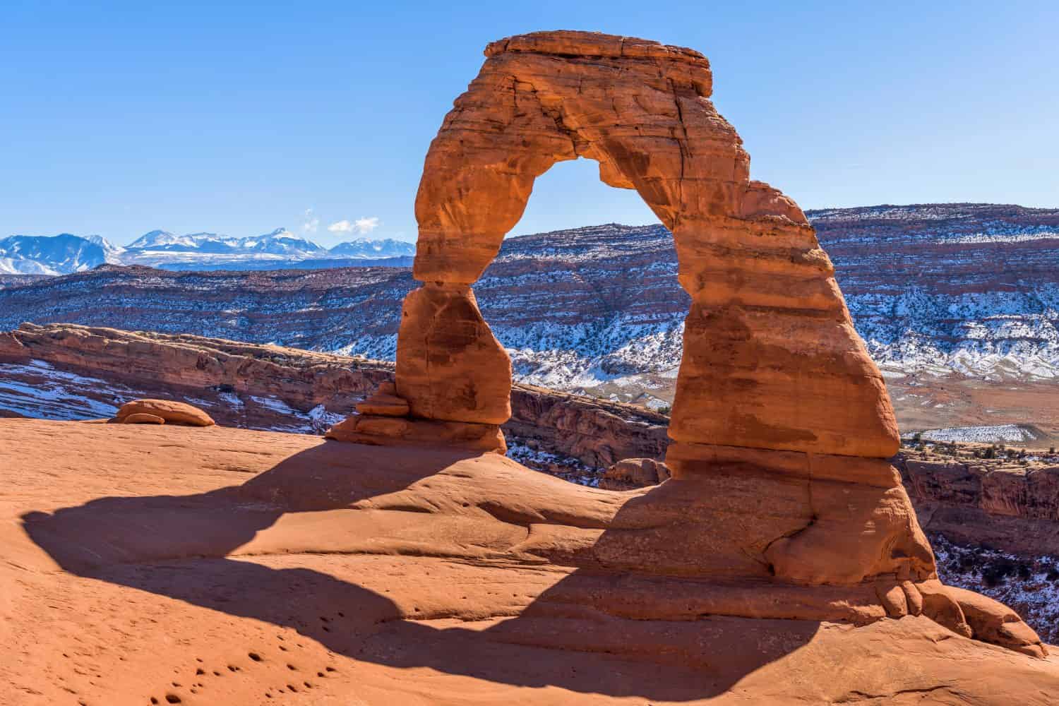 Winter Delicate Arch - A closeup view of Delicate Arch, with snow-covered La Sal Mountains towering in background, on a clear sunny Winter day. Arches National Park, Utah, USA. 