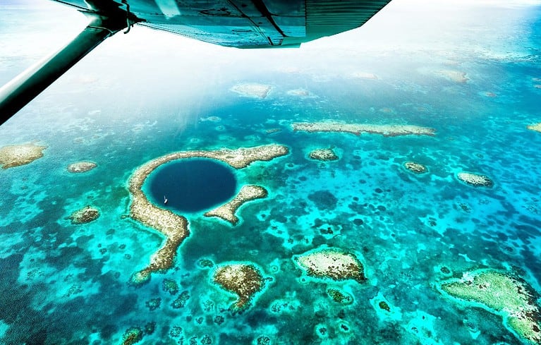 Aerial panoramic view of The Great Blue Hole - Detail of Belize coral reef from airplane excursion - Wanderlust and travel concept with nature wonders on azure vivid filter