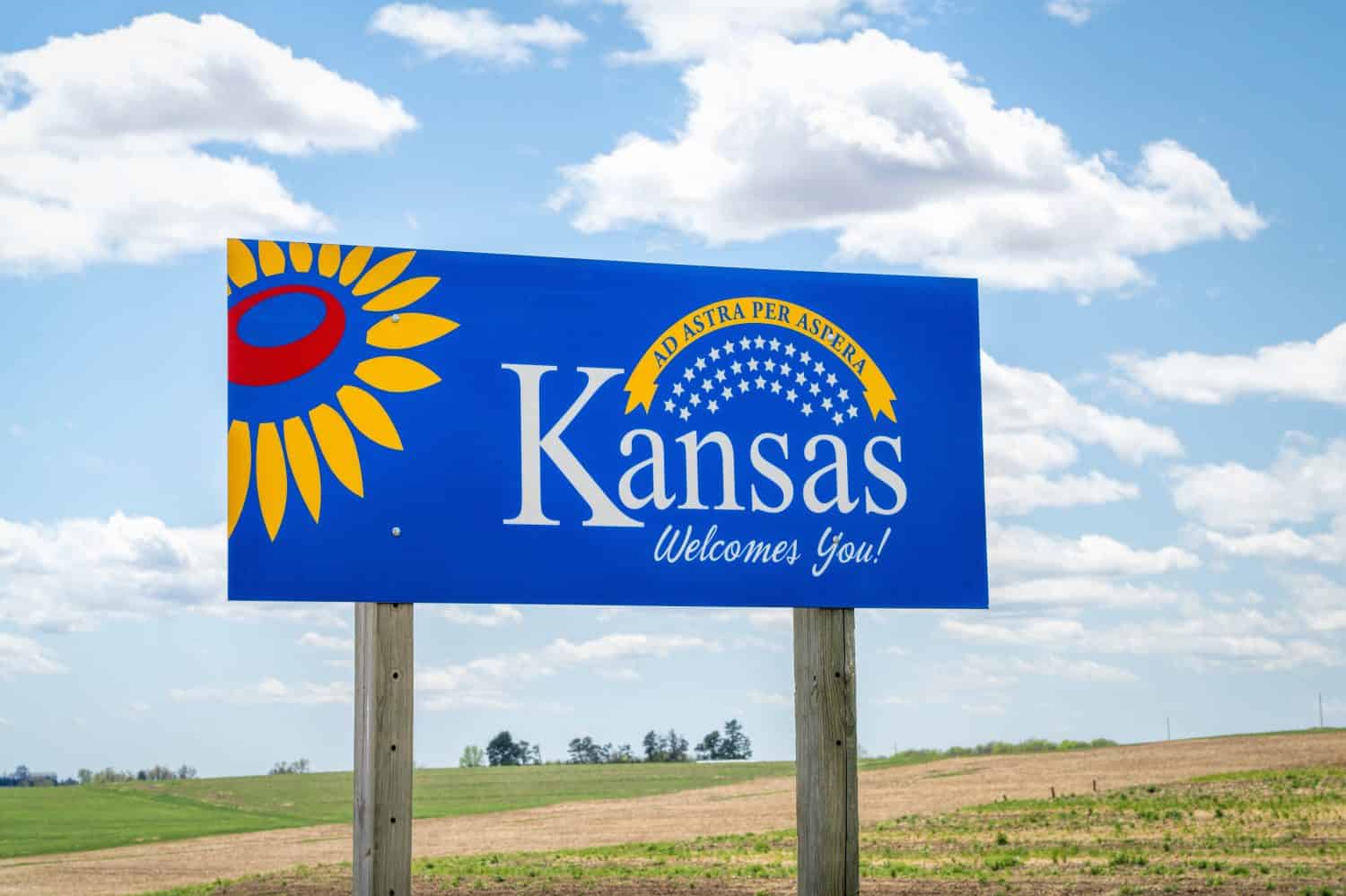 Kansas welcomes you - welcome roadside sign with a popular Latin phrase ad astra per aspera (through hardships to the stars), driving and travel concept