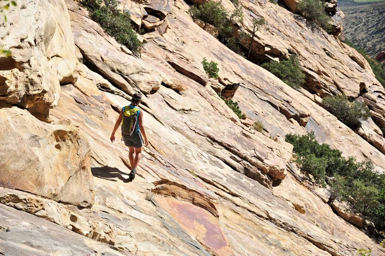 Young female rock climber crossing steep rockface, Mount Wilson, Nevada, USA