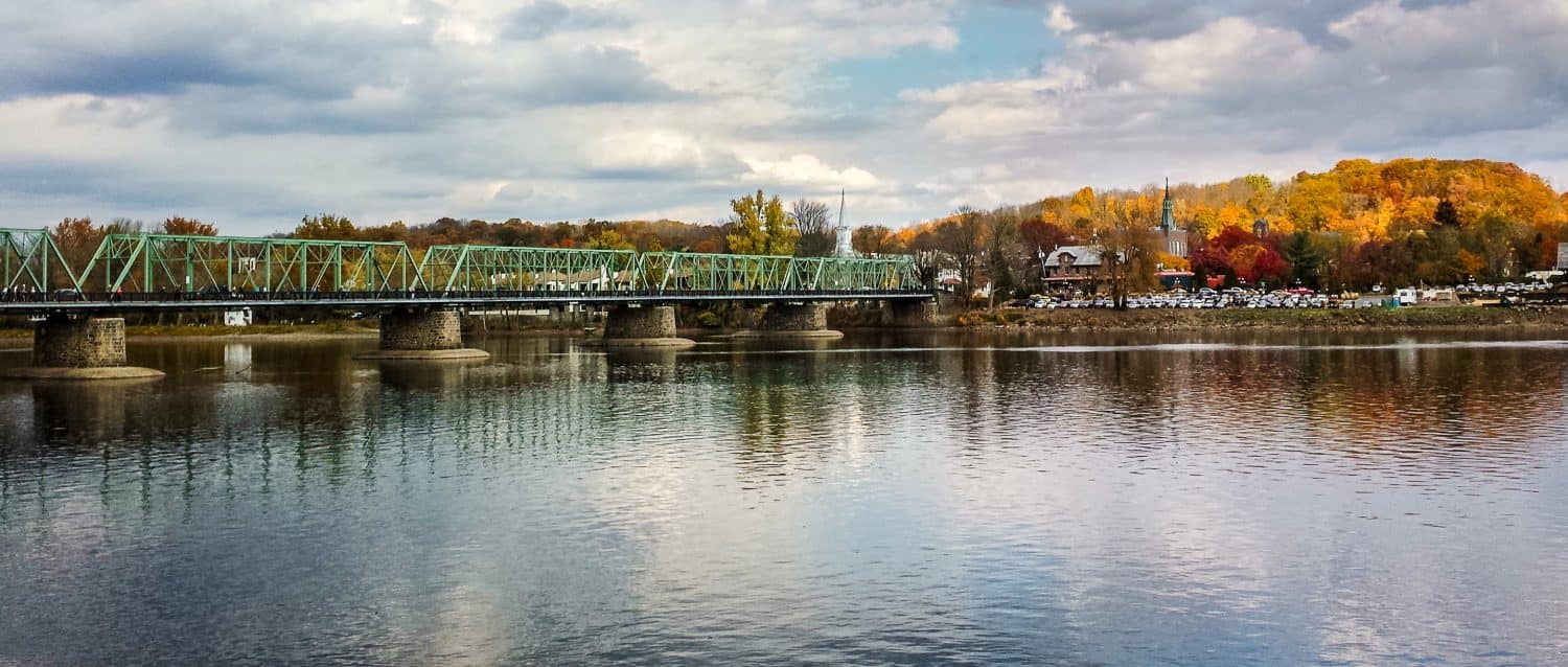 Panorama of a bridge across the Delaware River from New Hope, PA to Lambertville, NJ in autumn under a cloudy sky