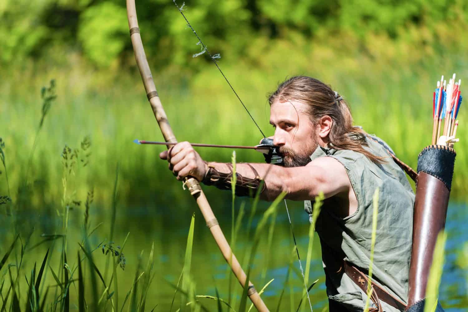Archer man shooting the bow and arrow in the swamp.Copy space