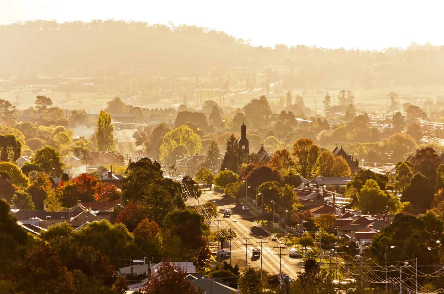 This is the town of Glen Innes in New South Wales, Australia. Morning mist fills rural town full of trees in autumn colors.