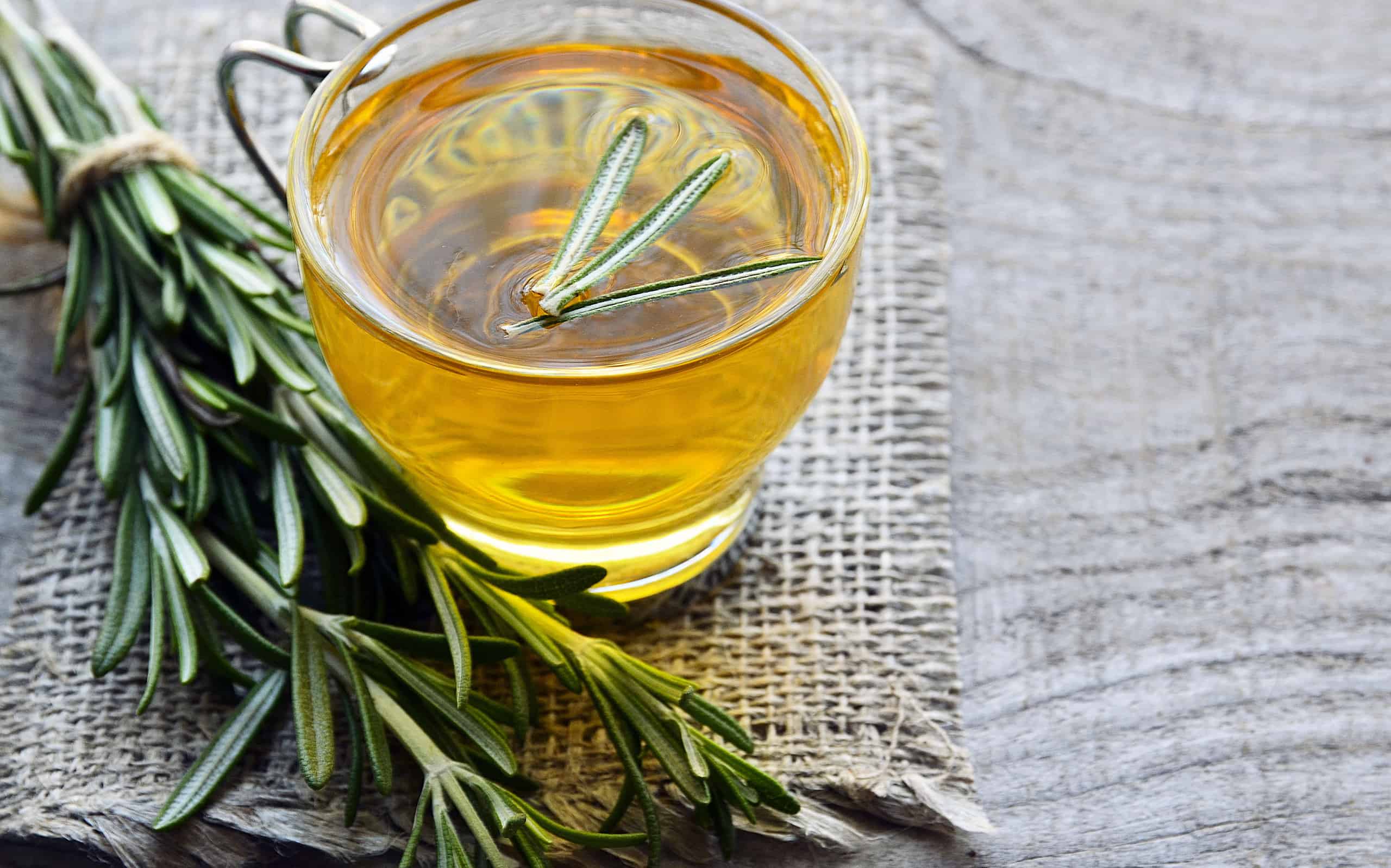 Rosemary herbal tea in a glass cup on rustic wooden background with copy space.Rosemary tea.Selective focus.