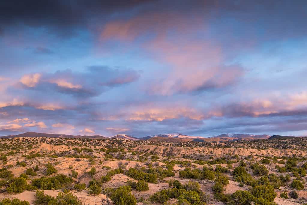 Dramatic colorful clouds over a desert and mountain landscape at sunset