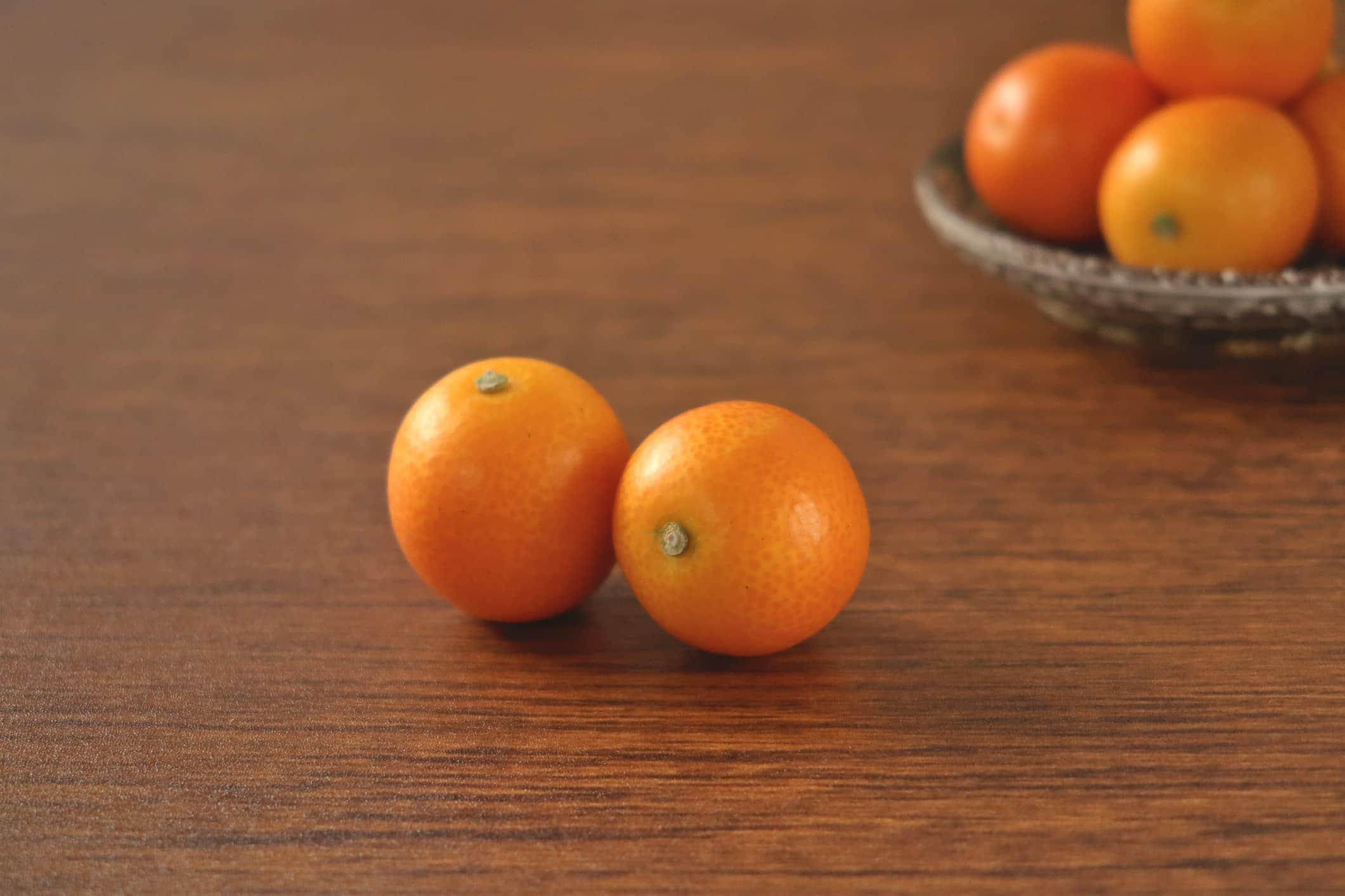 There are kumquats on the table and on the plate.