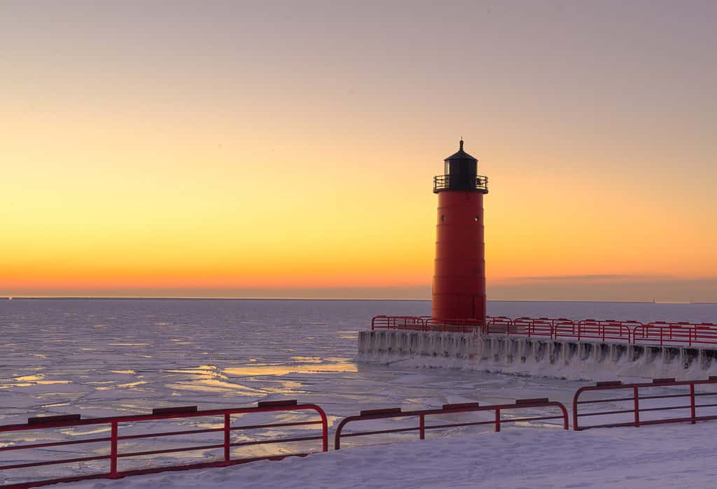 Red lighthouse on Lake Michigan in Winter at sunrise