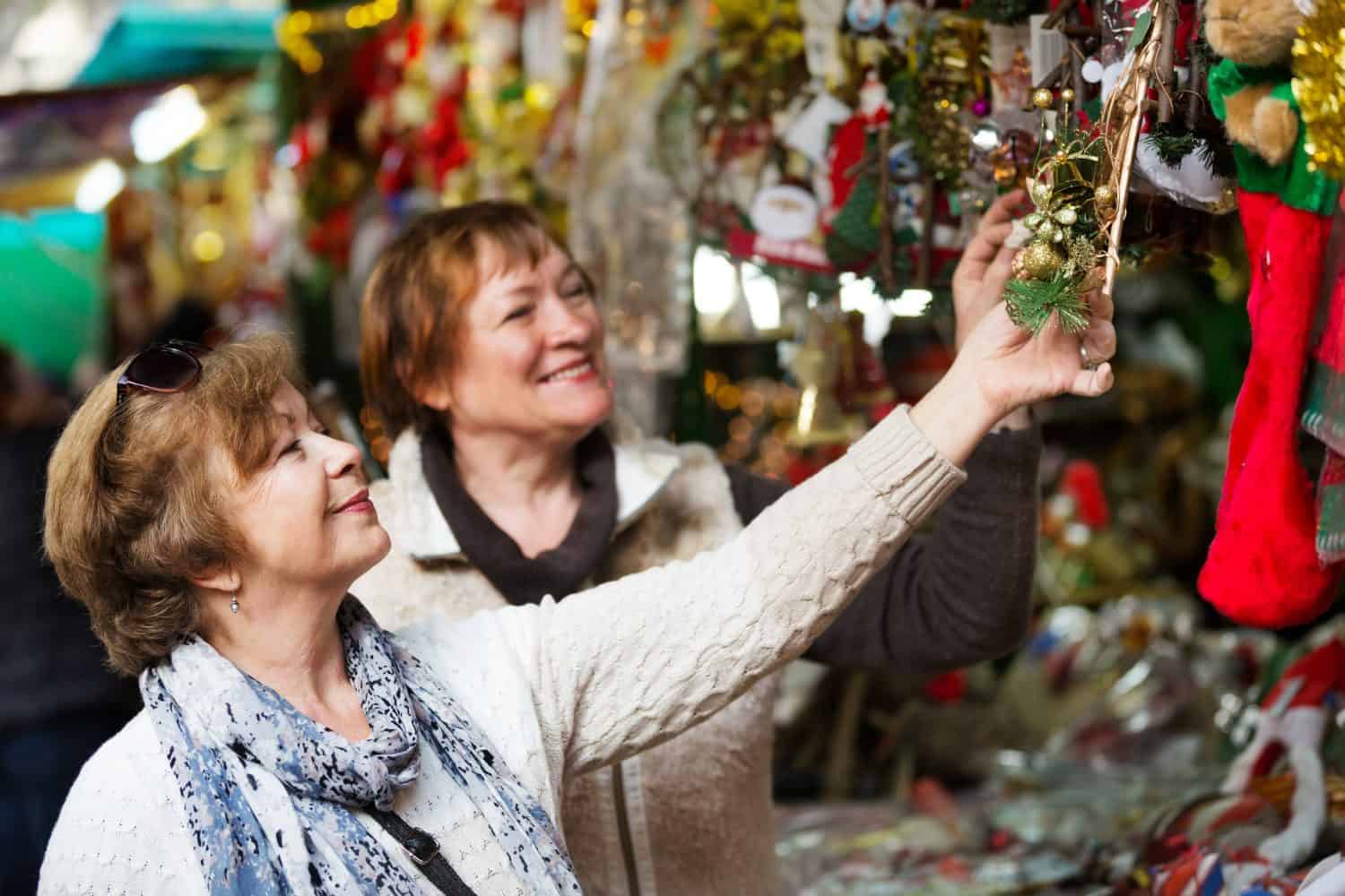 Cheerful female pensioners buying a X-mas decorations and souvenirs at fair 