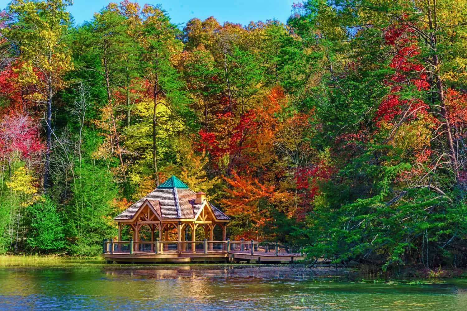 Colorful fall colors reflect along the shoreline where a gazebo sits in a little cove of Bay Mountain Lake Park in Kingsport Tennessee.