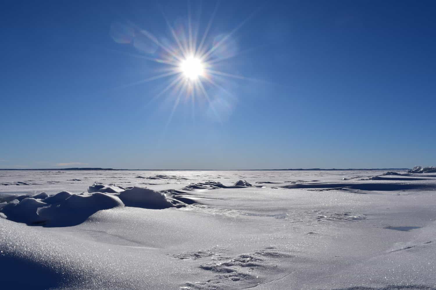 view over frozen lake on a sunny winter day with blue sky and snow on ice glittering in sunlight at Fort Peck Lake in Montana