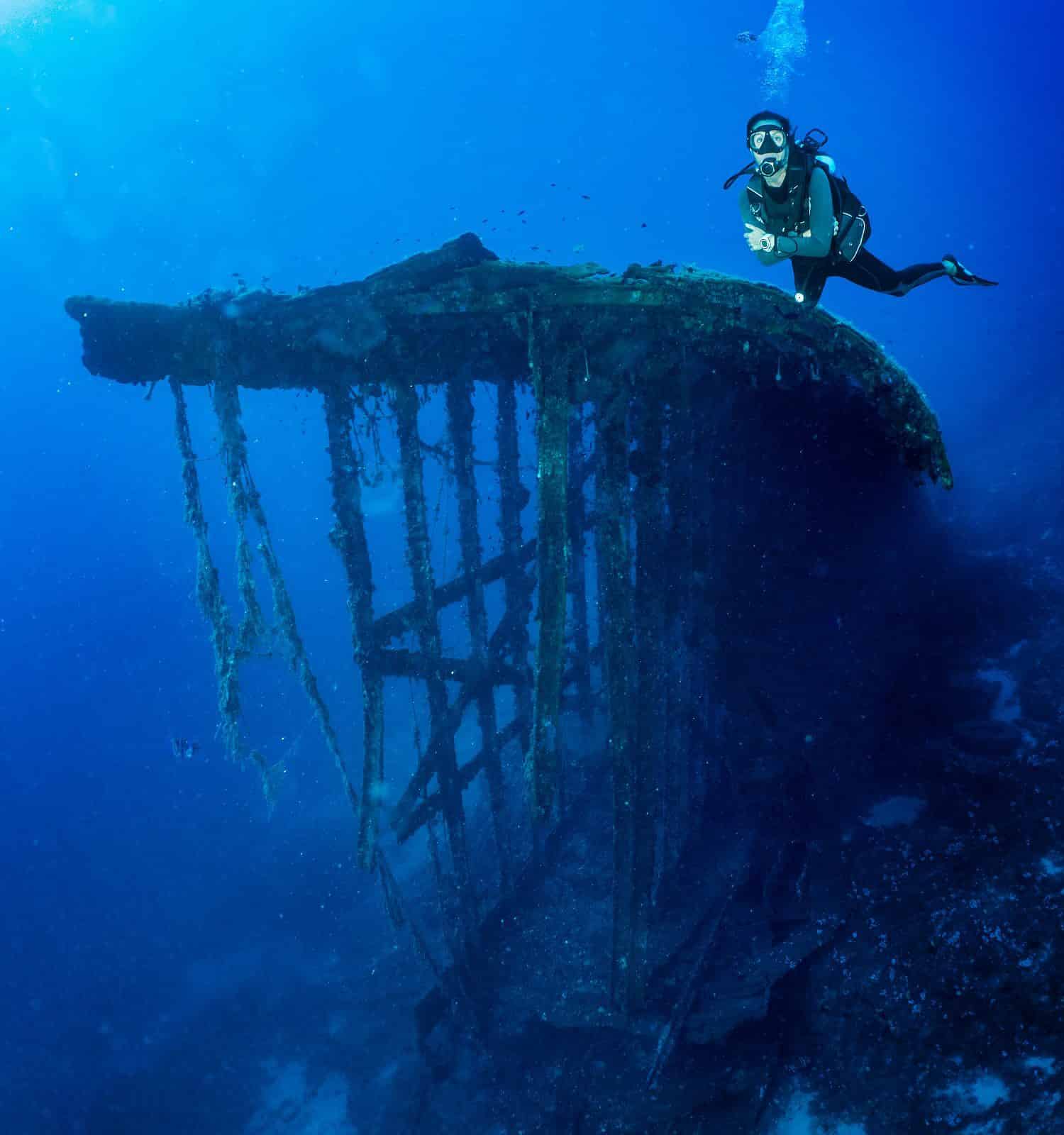 A scuba diver in front of an old, sunken shipwreck in the Aegean sea, Greece