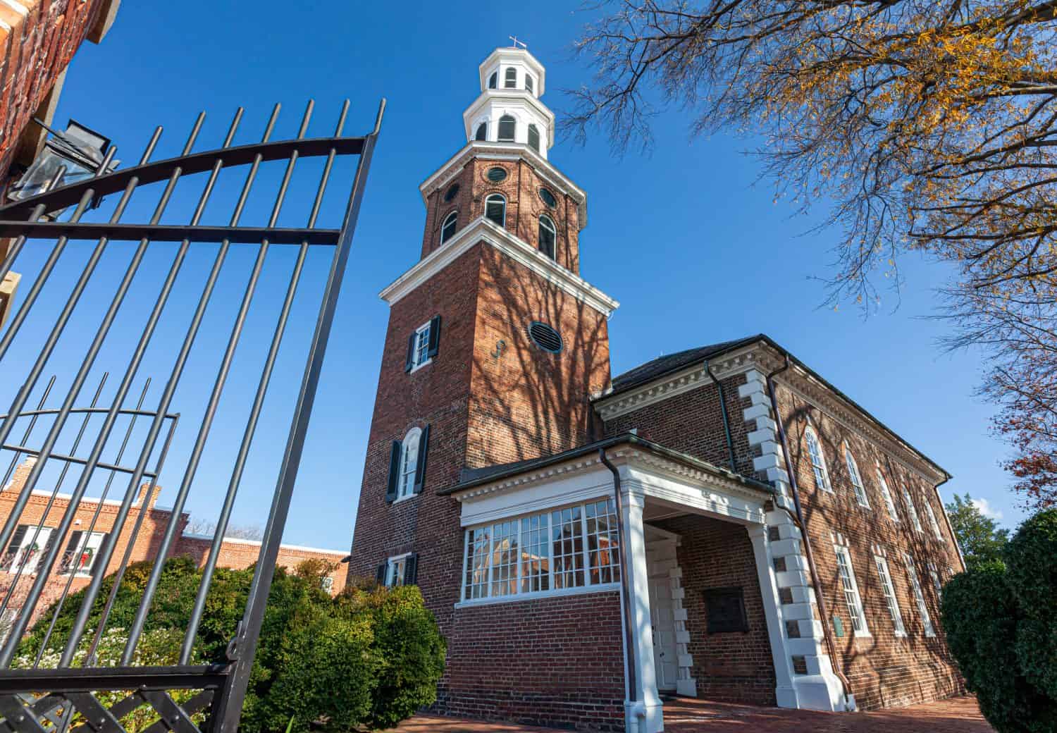 Close up image of the  entrance of historic Christ Church. This brick building with a tower was built in 1773 as the main Church of England in the neighborhood. There is a tall metal gate in the front