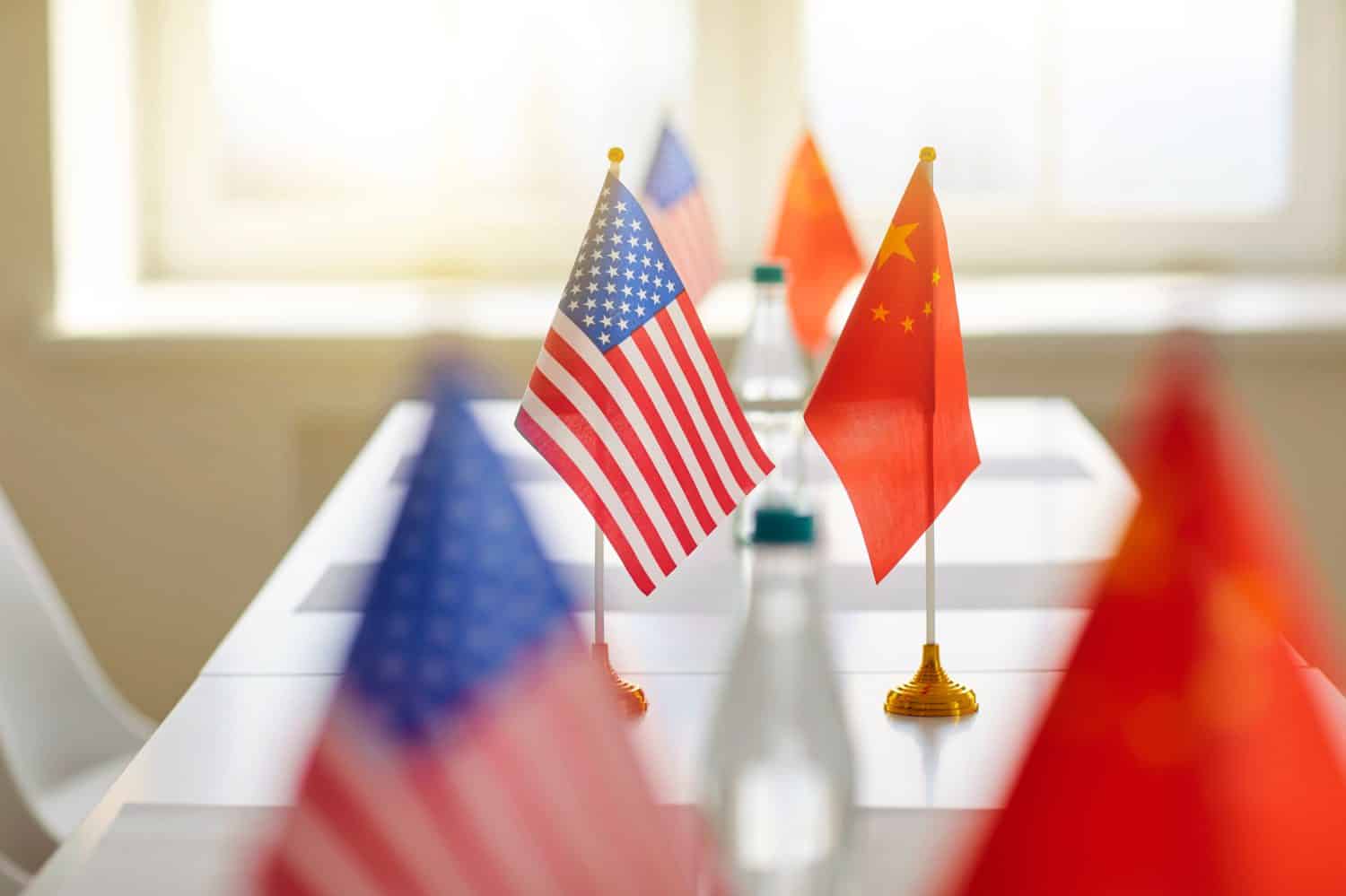 Negotiations between China and America. Close up of flags of China and United States on table at meeting to discuss trade relations. Concept of international relations. Selective focus.
