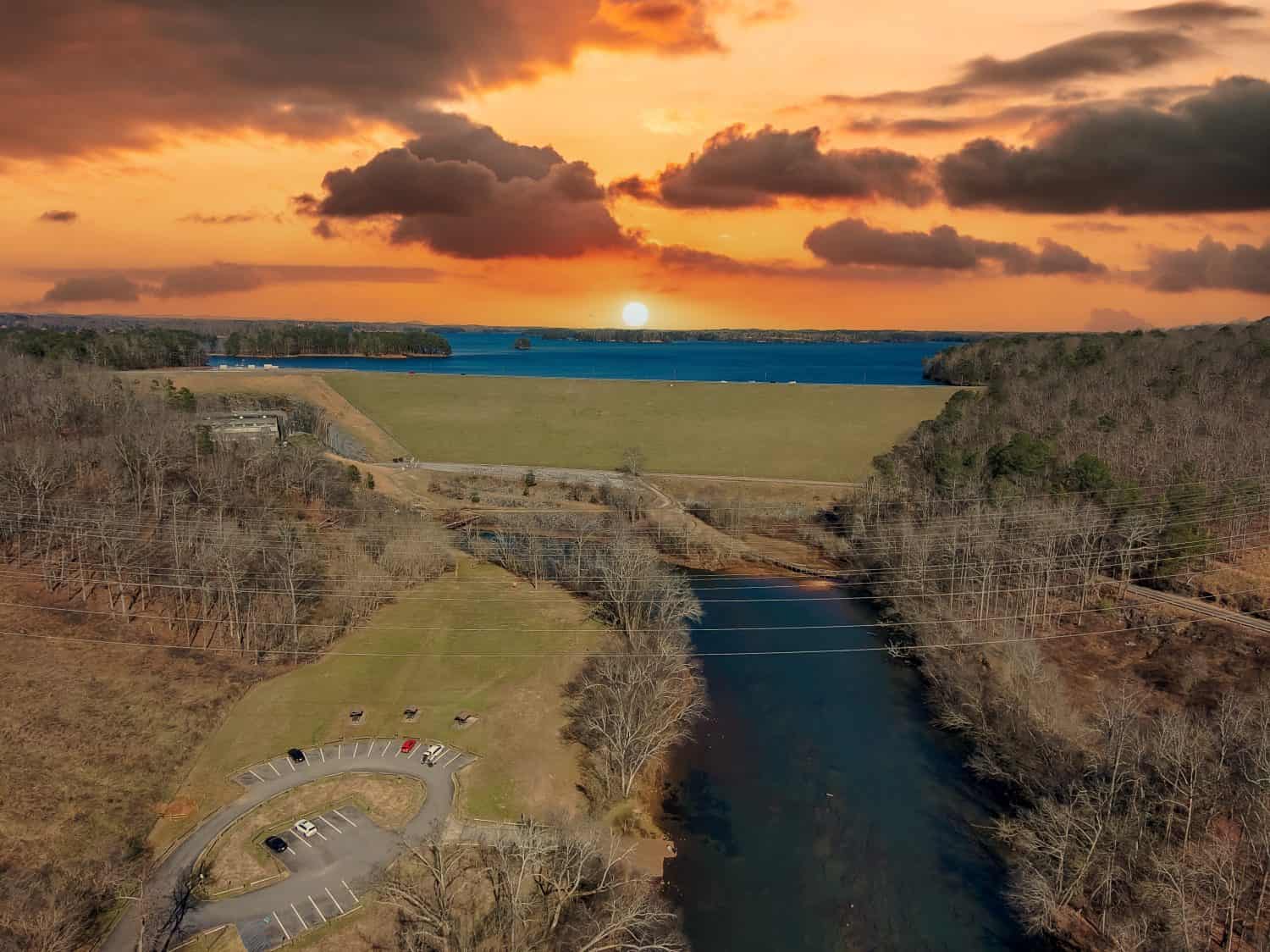 an aerial shot of the flowing waters of the river at Lower Pool West at Lake Lanier with bare winter trees and powerful clouds at sunset in Cummings Georgia USA