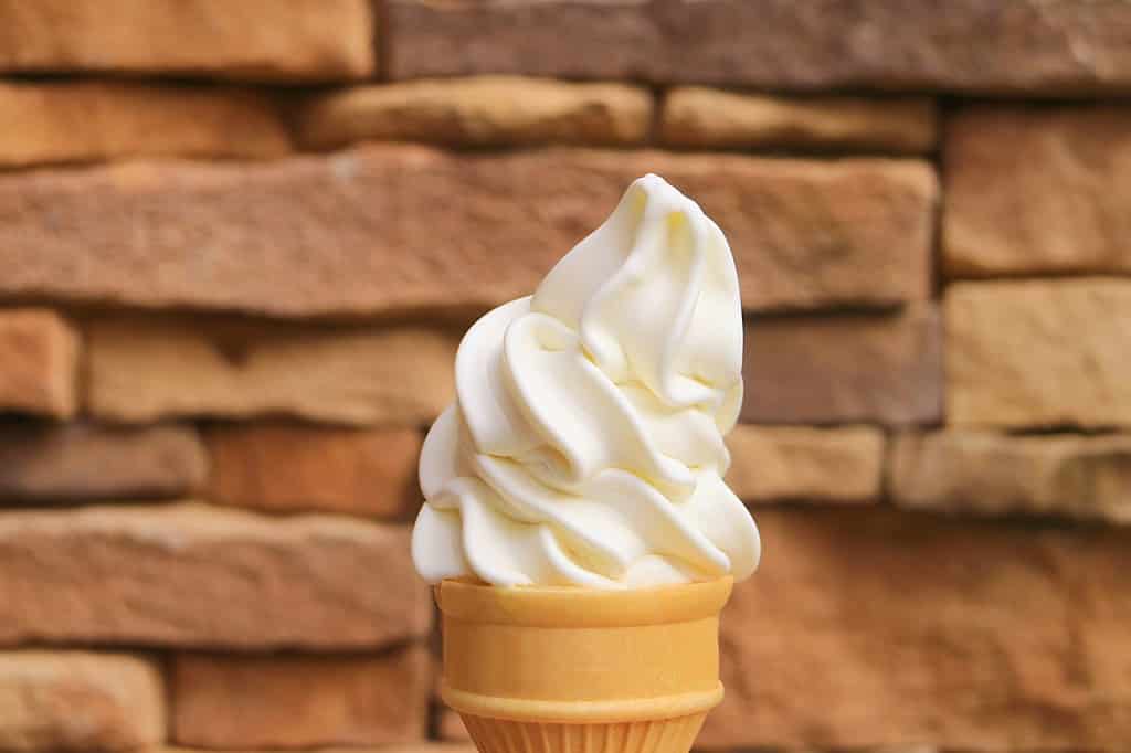 Delectable Vanilla Soft Serve Ice Cream Cone with Blurry Stone Blocked Wall in the Backdrop