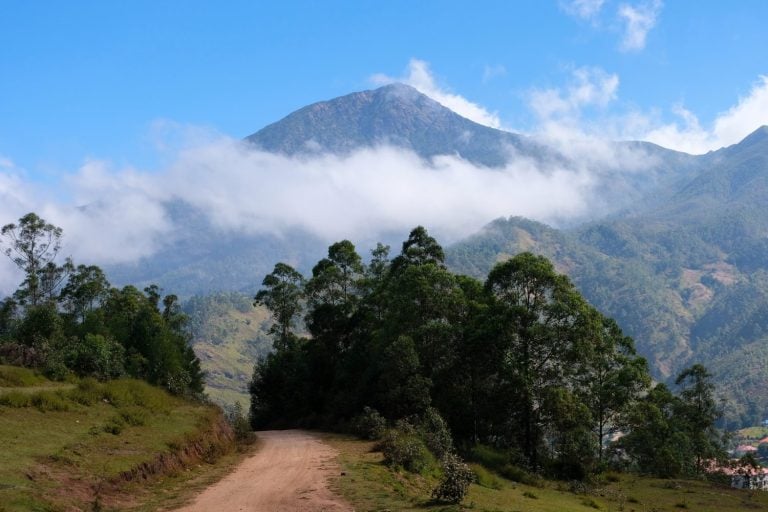 Scenic view of highest mountain in Timor-Leste, Mount Ramelau, with white clouds, blue skies and rugged tree covered landscape