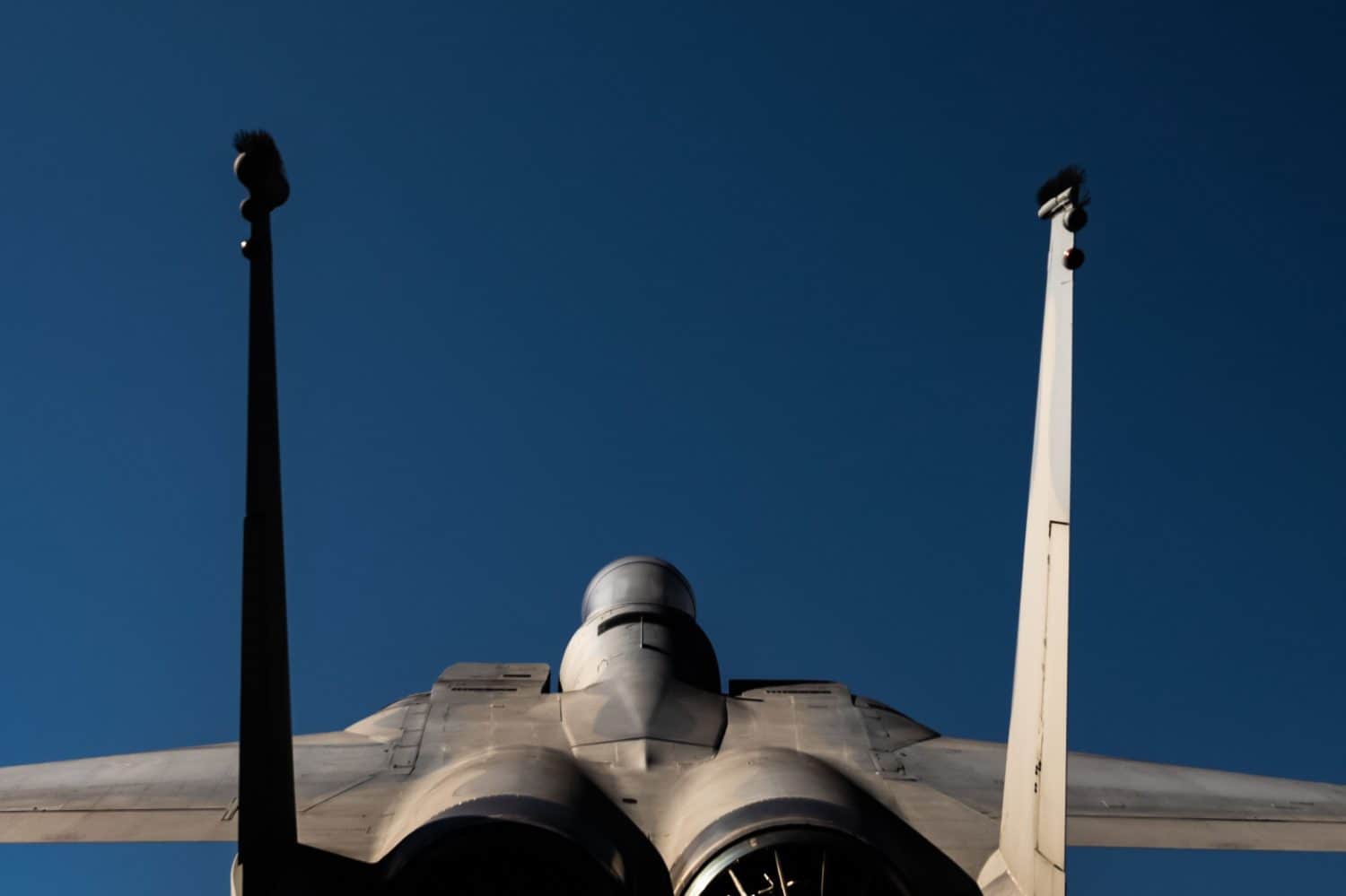 A closeup of rear of military supersonic jet F-15 eagle blue sky background