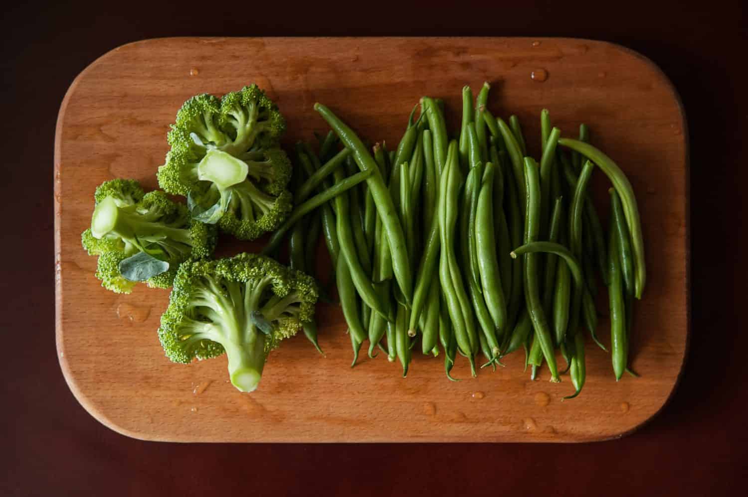 broccoli and green beans on a wooden board