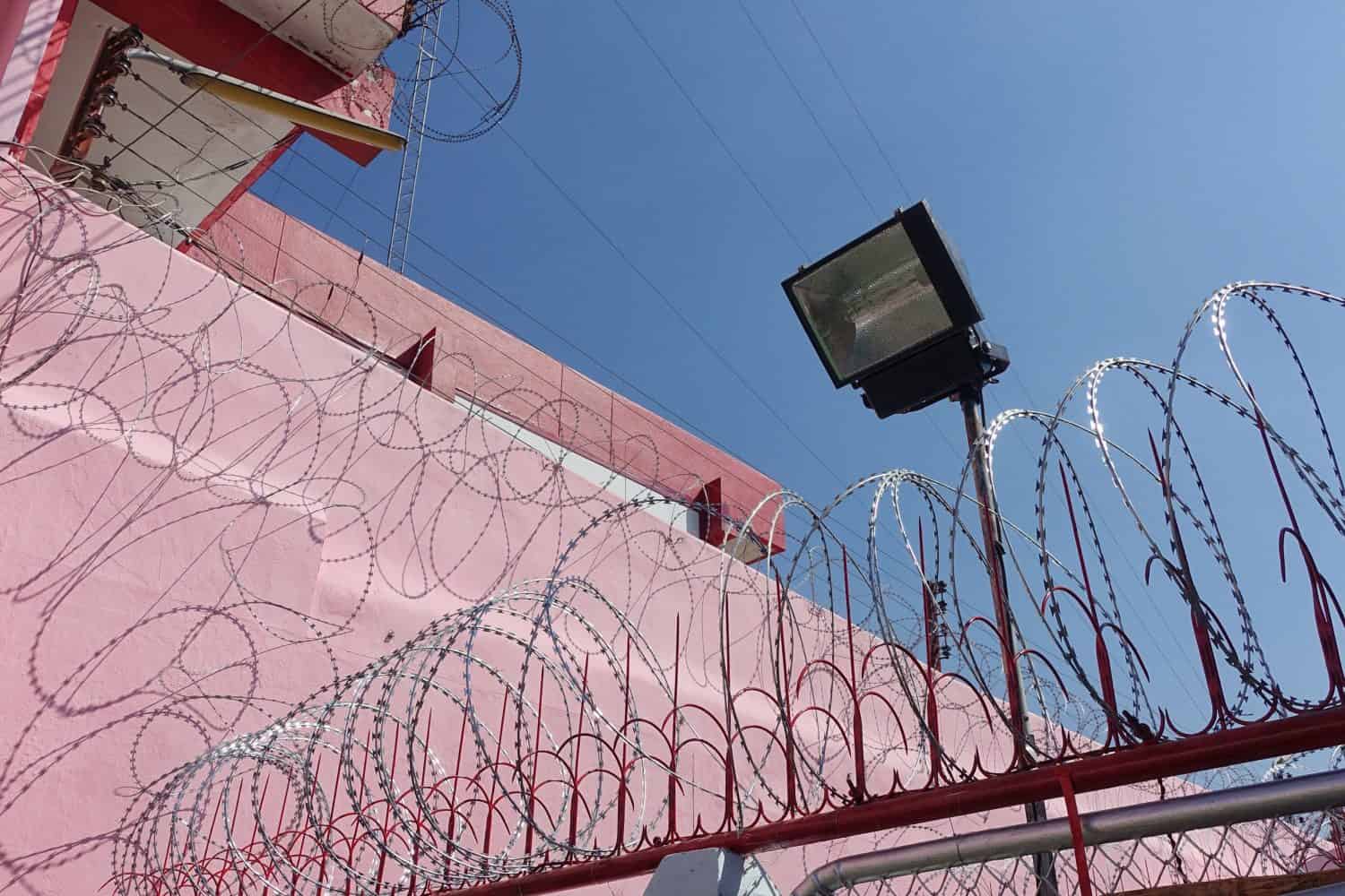 the pink and red prison walls of female prison building with high walls and barbed iron wire.