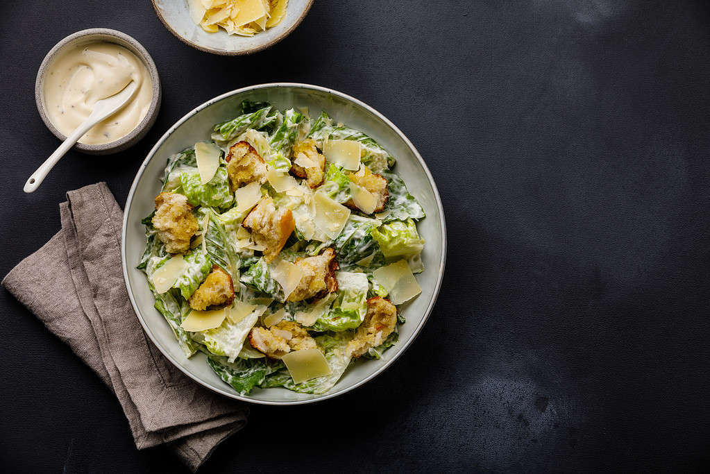 Caesar salad with croutons and parmesan cheese on dark background copy space