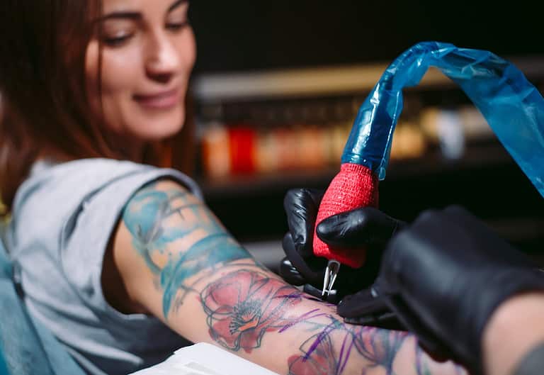 Professional tattoo artist makes a tattoo on a young girl's hand.