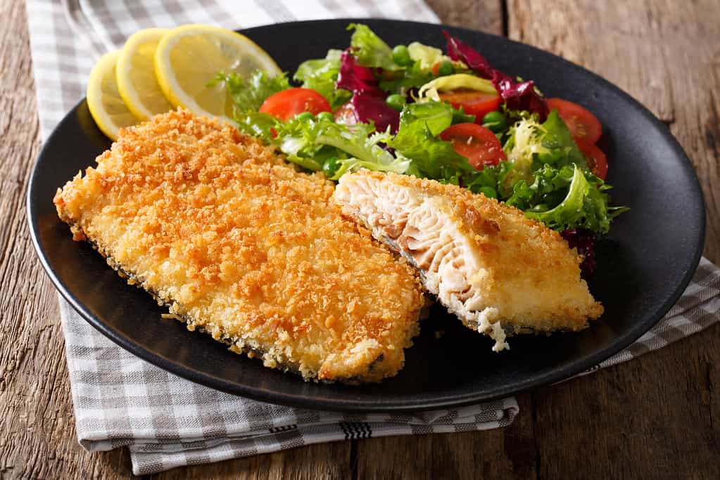 Tasty roasted Fish fillet in breadcrumbs and fresh vegetables close-up. horizontal