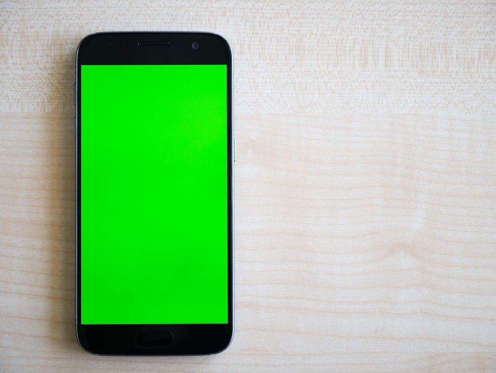 Android Smartphone with green screen vertically oriented shot top down on wood table