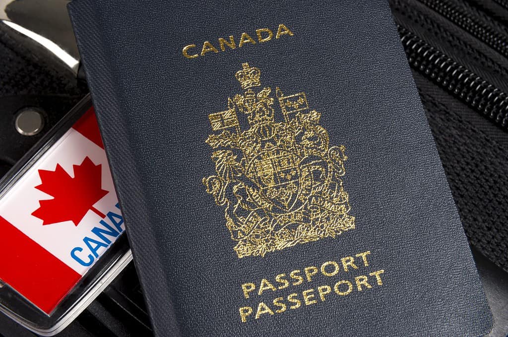 Closeup of Canadian passport sitting on suitcase with maple leaf luggage tag