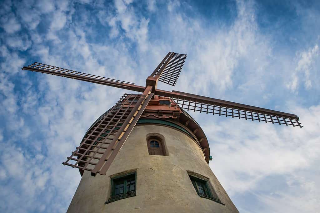 Low wide angle point of view image of Bevo Mill landmark windmill in St. Louis, Missouri, USA in early morning golden hour sun with blue sky and white clouds