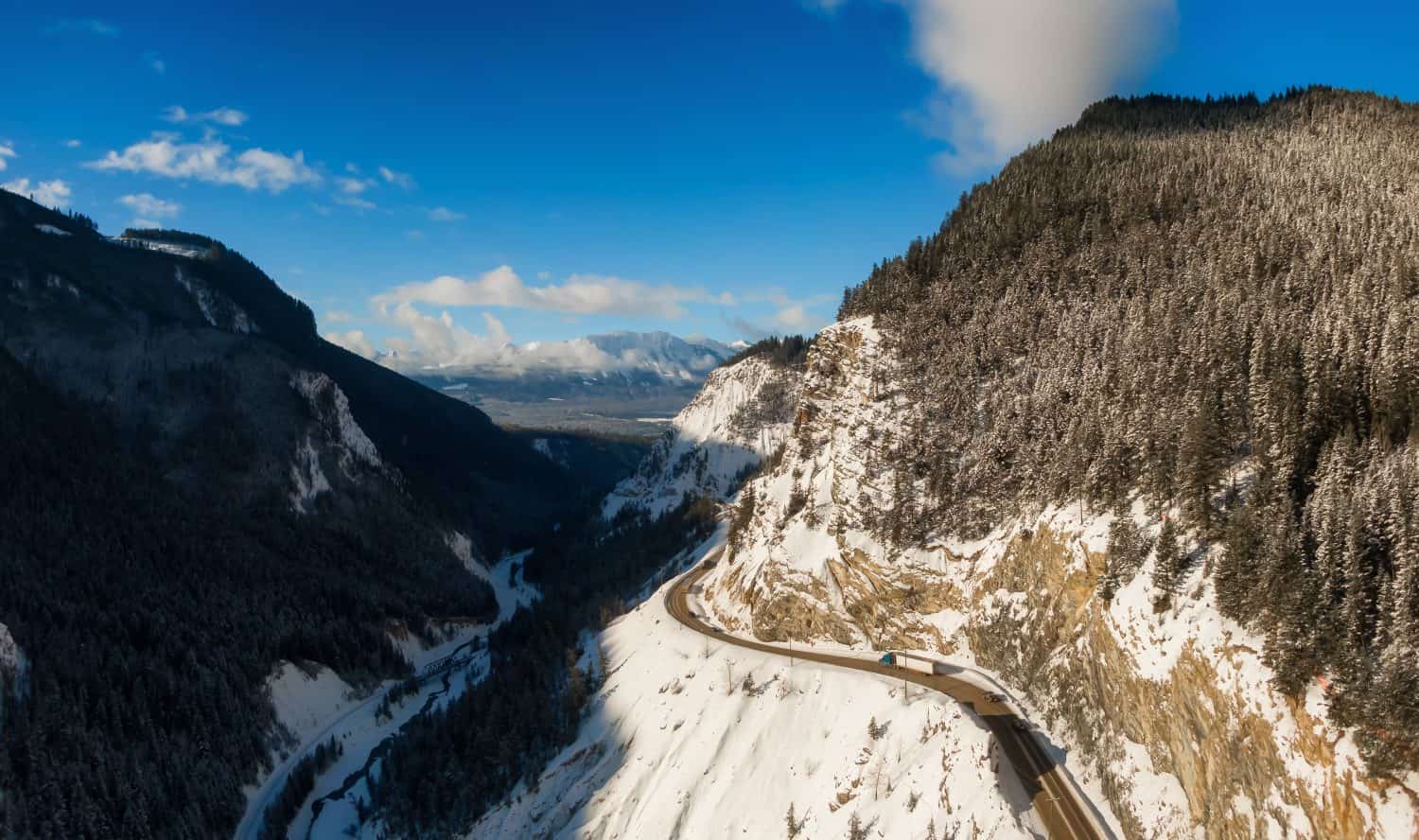 Aerial Panoramic View of a scenic Highway in the valley between Canadian Mountain Landscape during winter sunny sunrise. Taken near Golden, British Columbia, Canada.