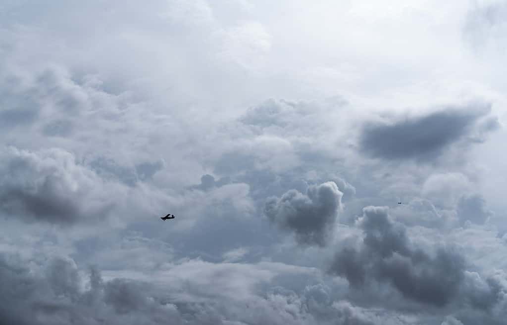 Small plane in cloudy sky for rainmaking. White fluffy clouds with small aircraft to make artificial rainfall. Two airplane flying on cloudy sky. Agricultural airplane for artificial precipitation.