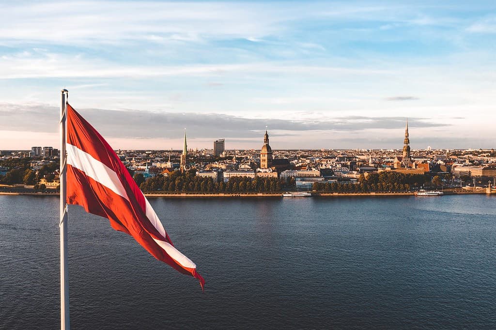 Huge Latvian flag flutters on wind with Riga old town in the background in Latvia. Patriotic video.
