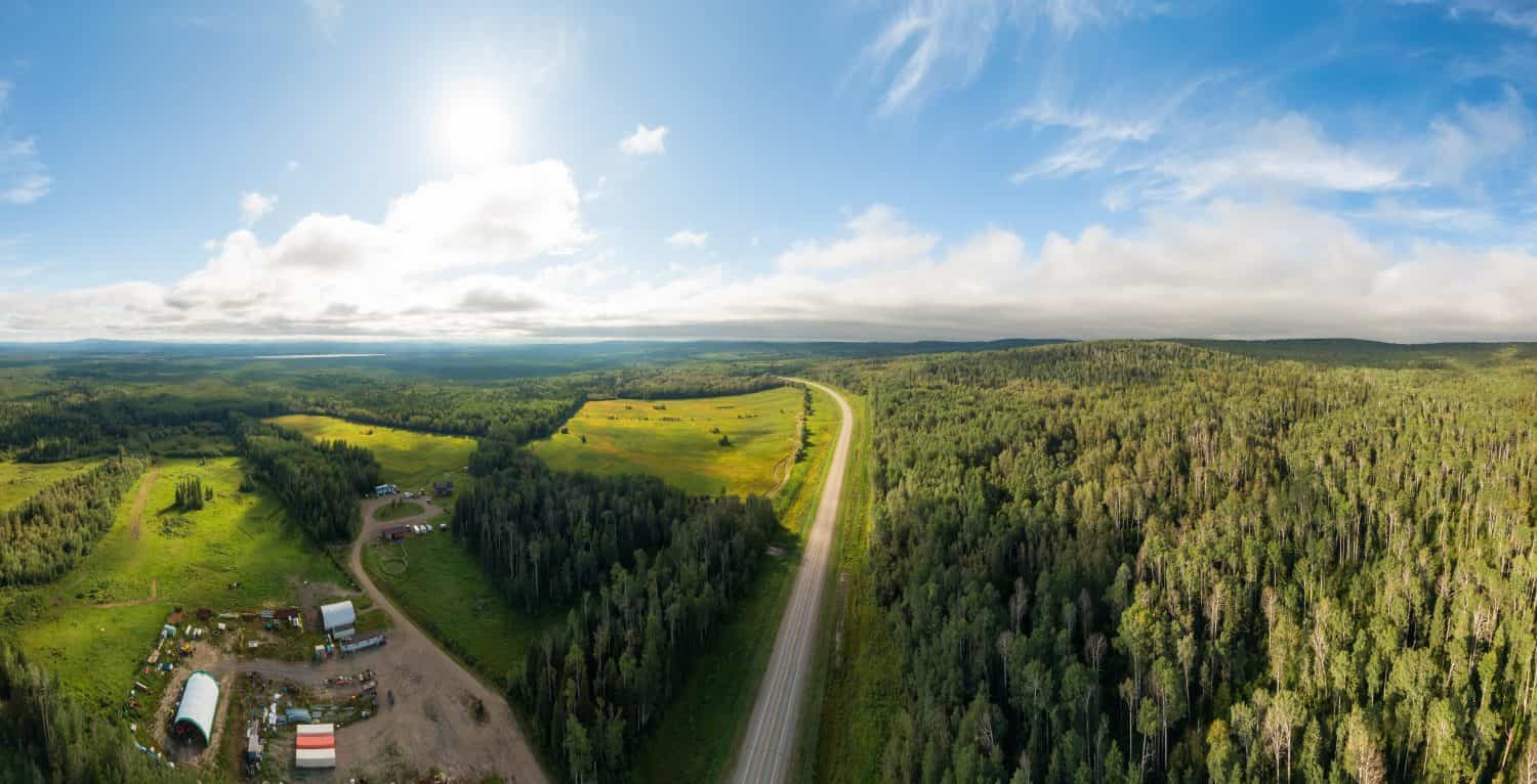 Scenic Panoramic Road View near Sunset surrouned by Forest, Farmland and Industry. Aerial Drone Shot. Northwest of Fort Nelson, Alaska Highway, Northern British Columbia.