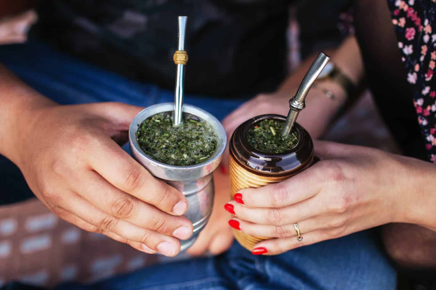 Yerba mate tea in bombilla. Special metal straw. Sout America popular hot drink. Couple drinking healthy herbal beverage. Engagement outdoor picnic.
