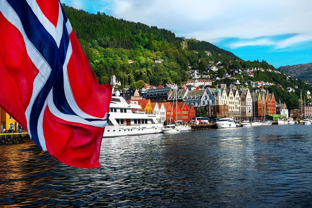 Norwegian flag with the port of Bergen and view on the historical buildings of Bryggen in Bergen, Norway