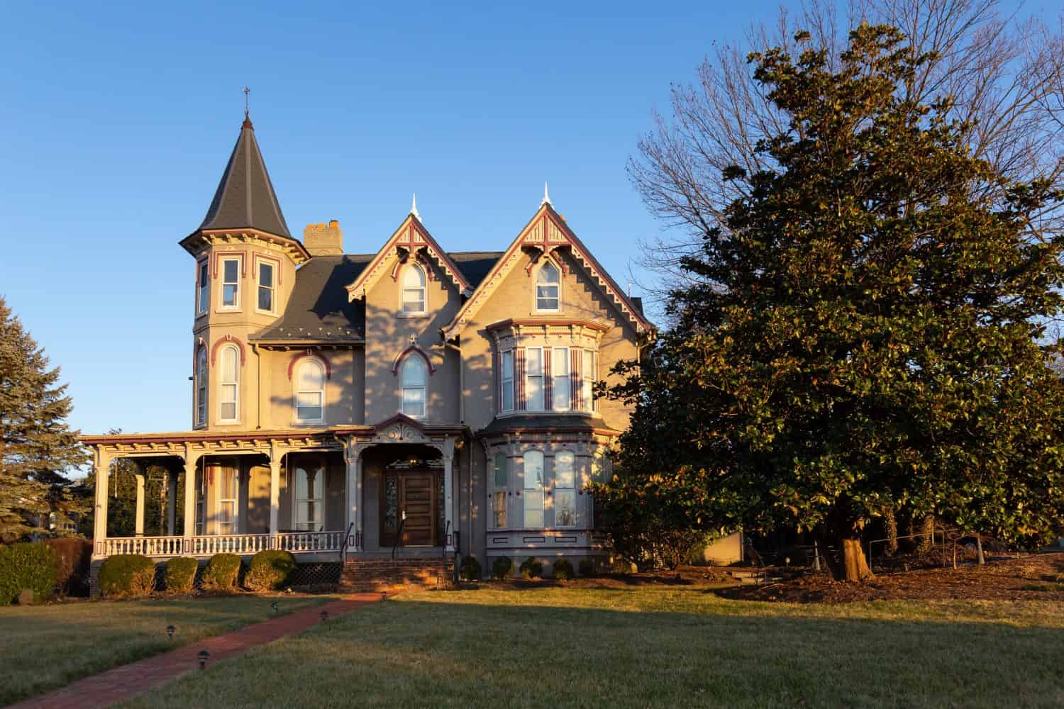 Beautiful Victorian style brick house with wooden details and tower seen during a golden hour winter afternoon, Harrisonburg, Virginia, USA
