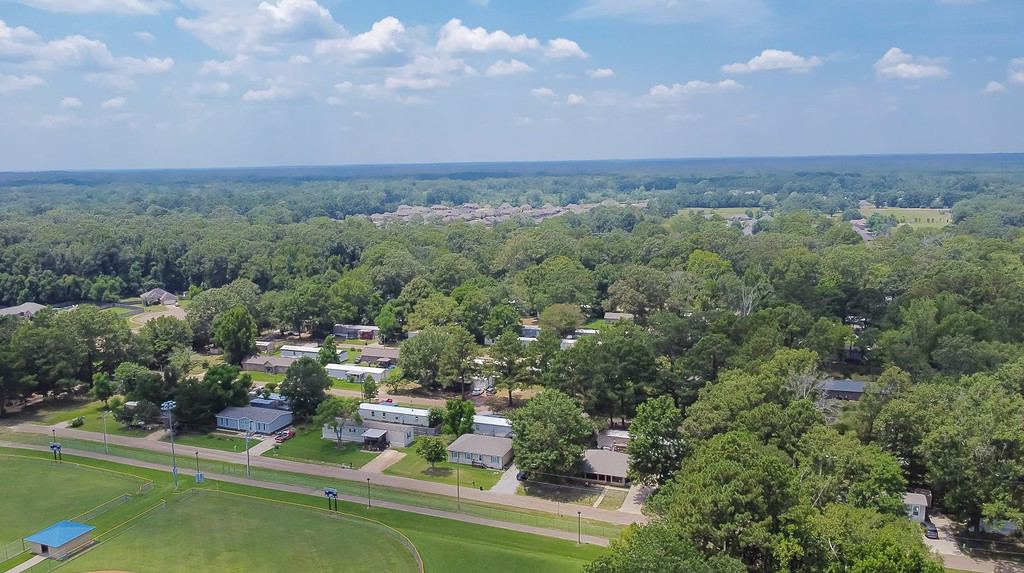 Large baseball fields near row of manufactured, modular, and mobile homes in Richland, Rankin County, Mississippi suburb of Jackson, lush green trees neighborhood. Aerial view affordable housing
