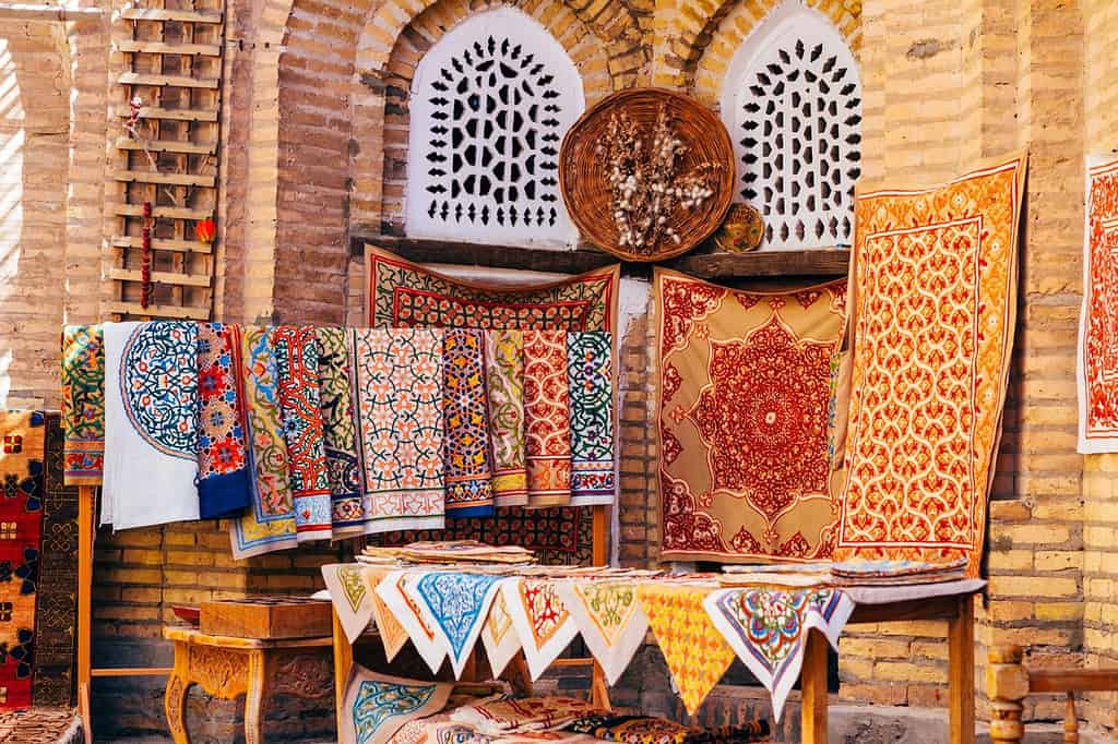 The wide range of the hand made carpets, traditional knotted Uzbek silk rugs, embroidered tablecloths and bed linen in the small bazaar, Khiva, Uzbekistan, Central Asia