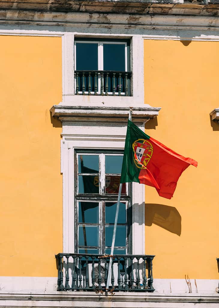 Portuguese flag on yellow facade reflecting on window