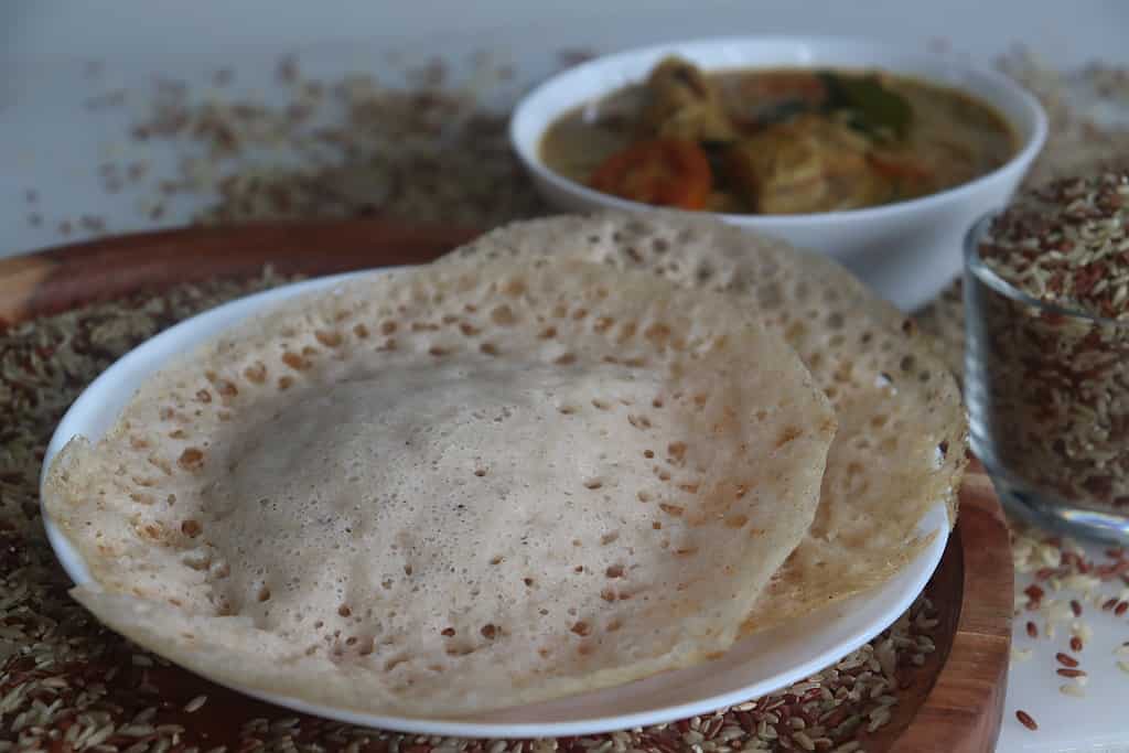 Rajamudi rice appam served with kerala chicken curry.