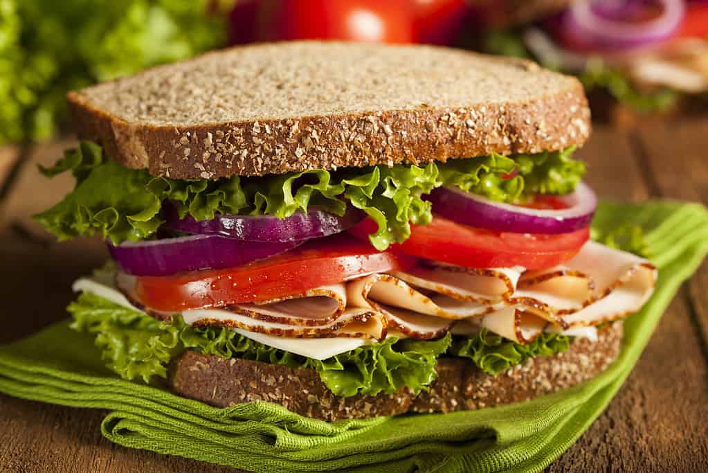 A sandwich with tomatoes, onions, and lettuce on wheat bread