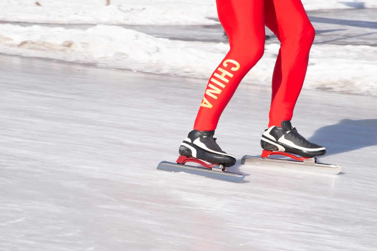 Young active man have a fun leisure skating on the icy lake with China tights in park of Shenyang. Close up of the red tights, boots, blades and legs. 