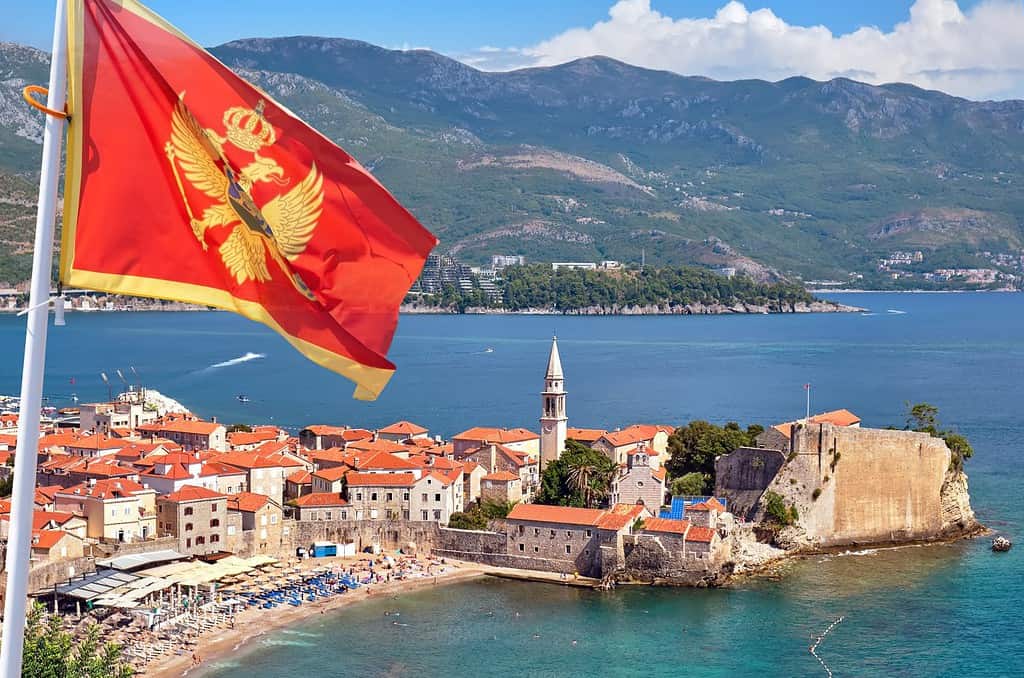 Old town in Budva against the background of a mountain landscape with the flag of Montenegro