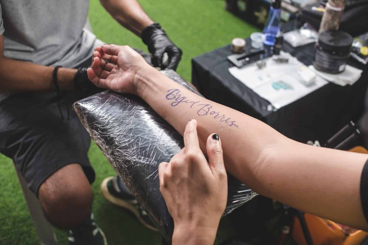 An outline of a cursive name on a client's forearm prior to the actual tattoo procedure.