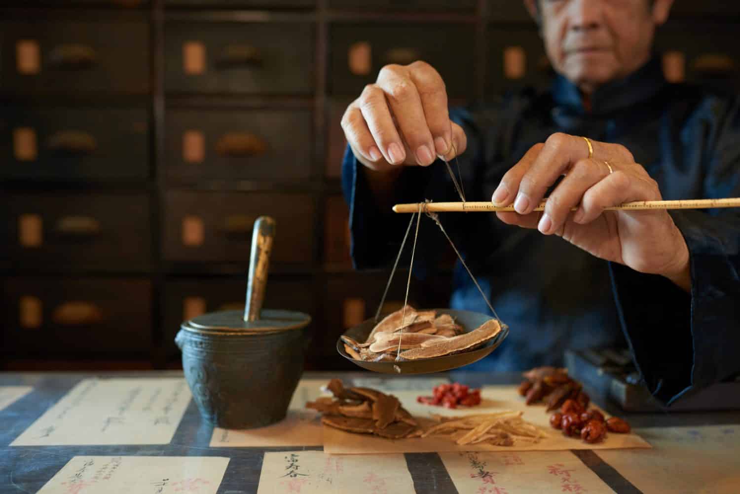 Man measuring ingredients in traditional Asian apothecary